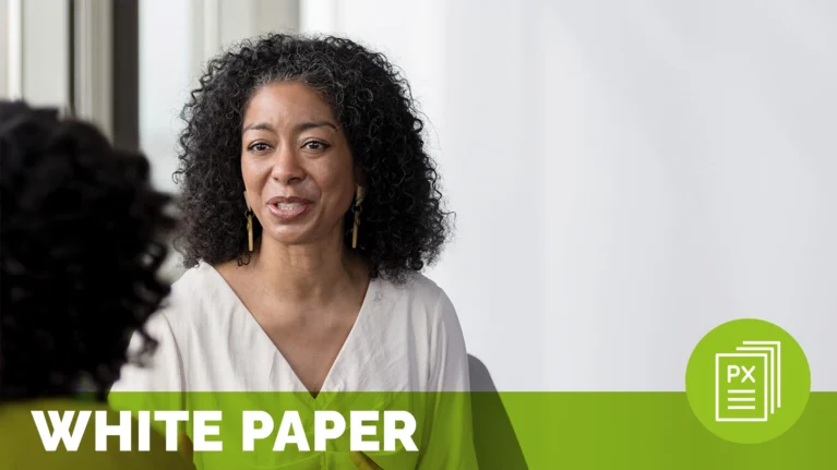 a woman with curly hair and a white shirt speaking to someone out of frame