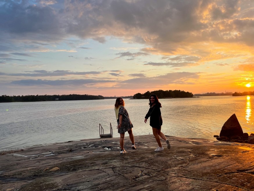 two women look back at the camera on a lakeside beach at sunset