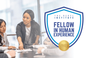 an image of a woman pointing to a file on a table; to her right, a shield graphic reads the beryl institute fellow in human experience