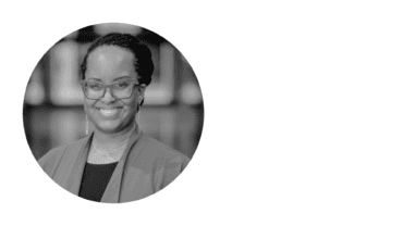 a black and white headshot of a smiling woman in glasses