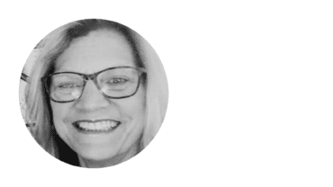 a black and white headshot of a smiling woman in glasses