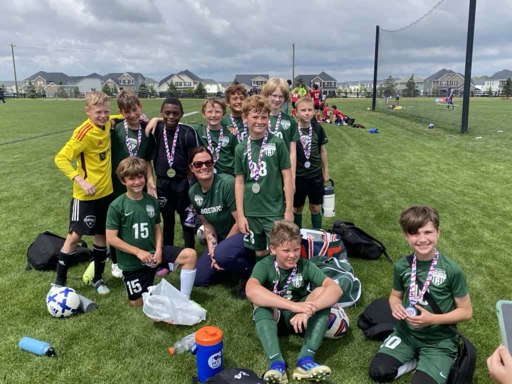 a little boys' soccer team in green grins with medals around their necks
