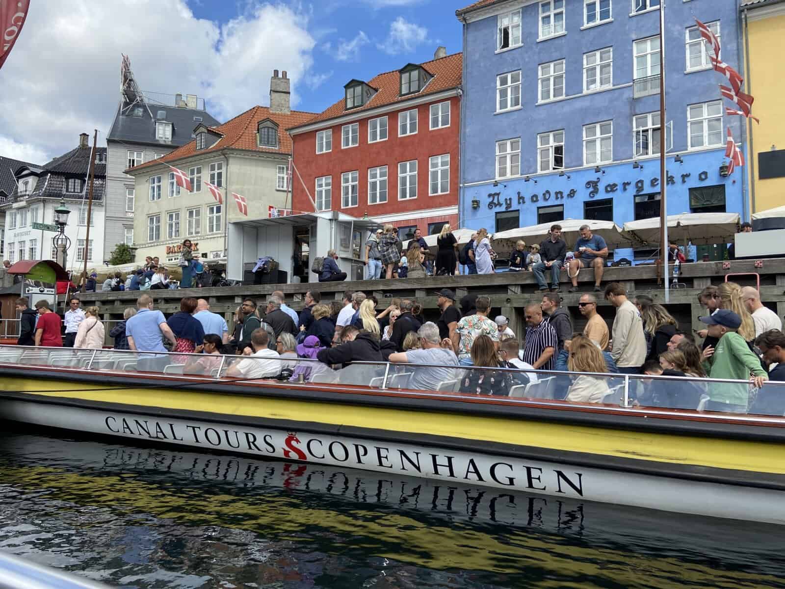 an image of a european cityscape, featuring a boat that has text on it that reads "canal tours copenhagen"