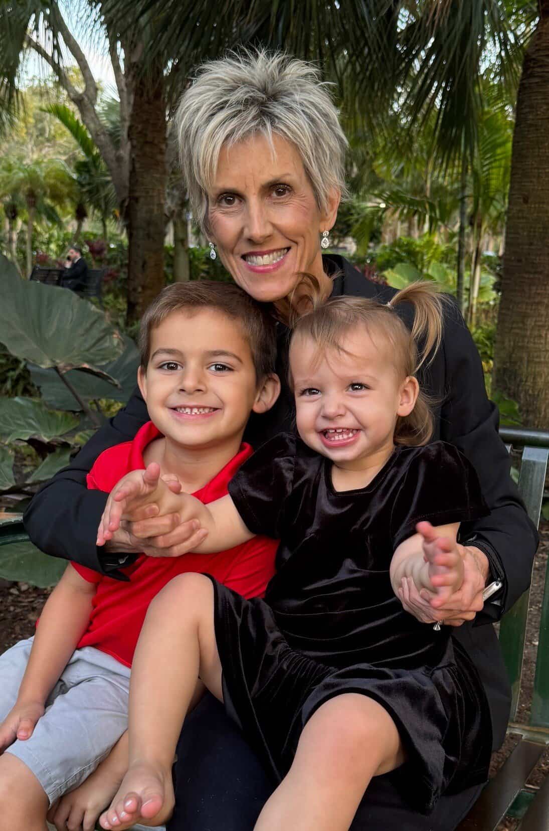 a woman smiles with two children on her lap